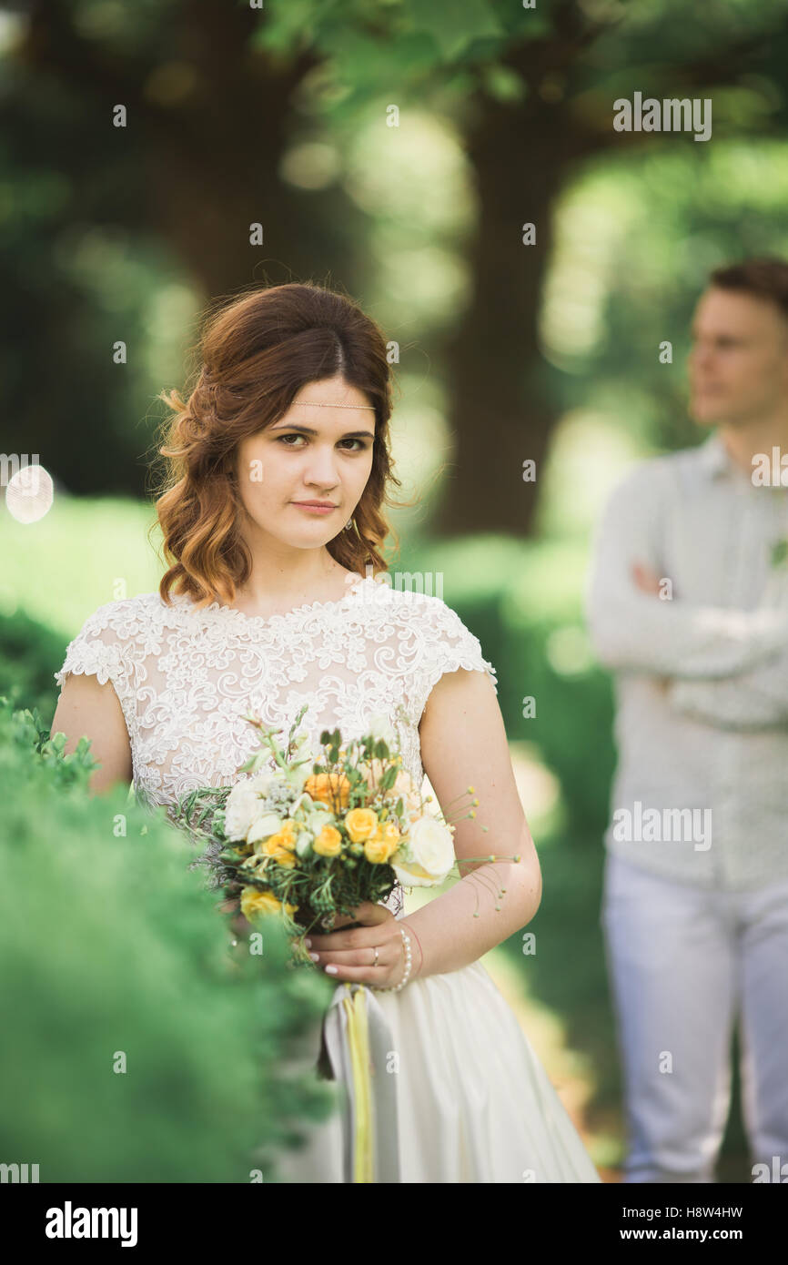 Sposa in posa e sorrisi mentre lo sposo attende sullo sfondo Foto Stock