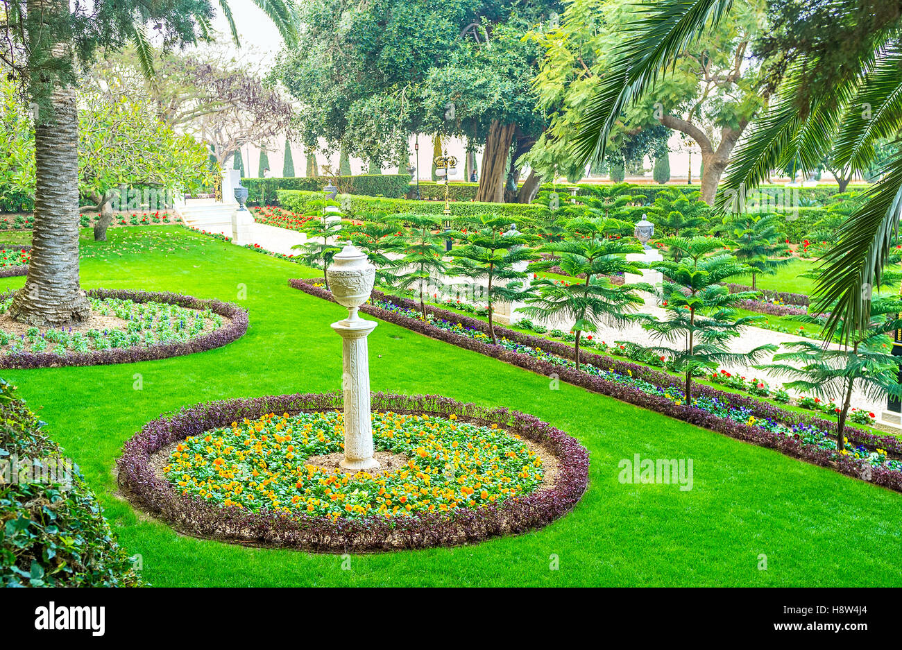 La pietra urna decorativo sulla snella colonna tra il letto di fiori del giardino Bahai, Haifa, Israele. Foto Stock