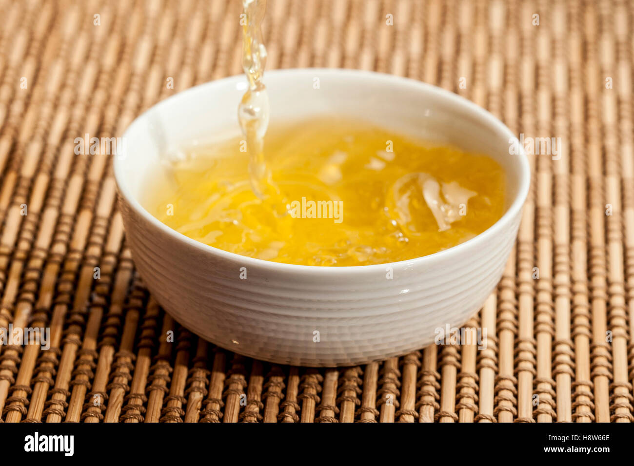 Spruzzi di tè in tazza giapponese sul tappetino Foto Stock