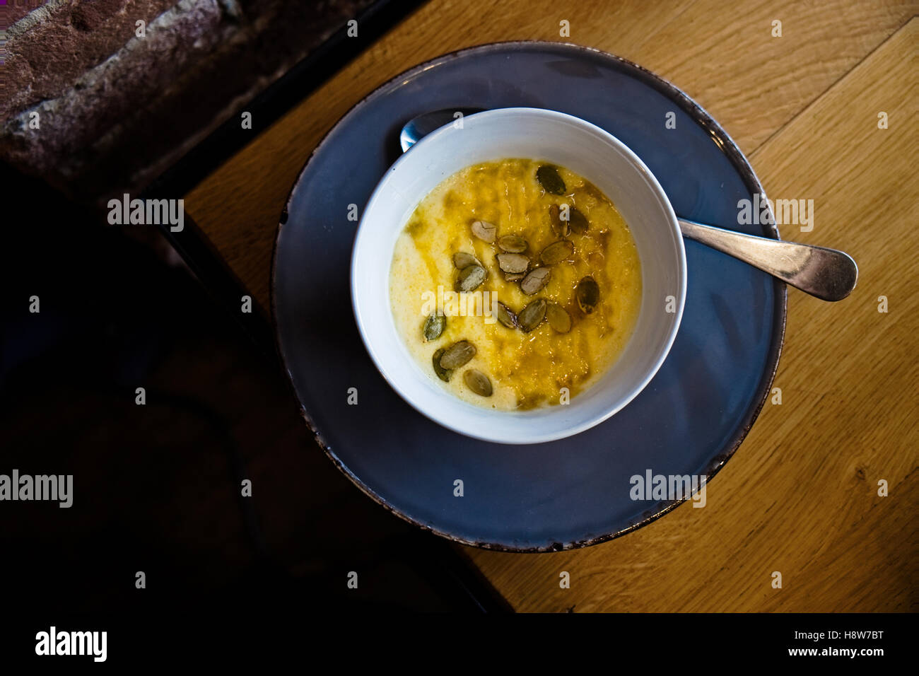 Polenta sani porridge ciotola con i semi di zucca e miele su una lastra grigia. Caldo autunno e inverno la colazione. Un tavolo di legno. Parte superiore Foto Stock