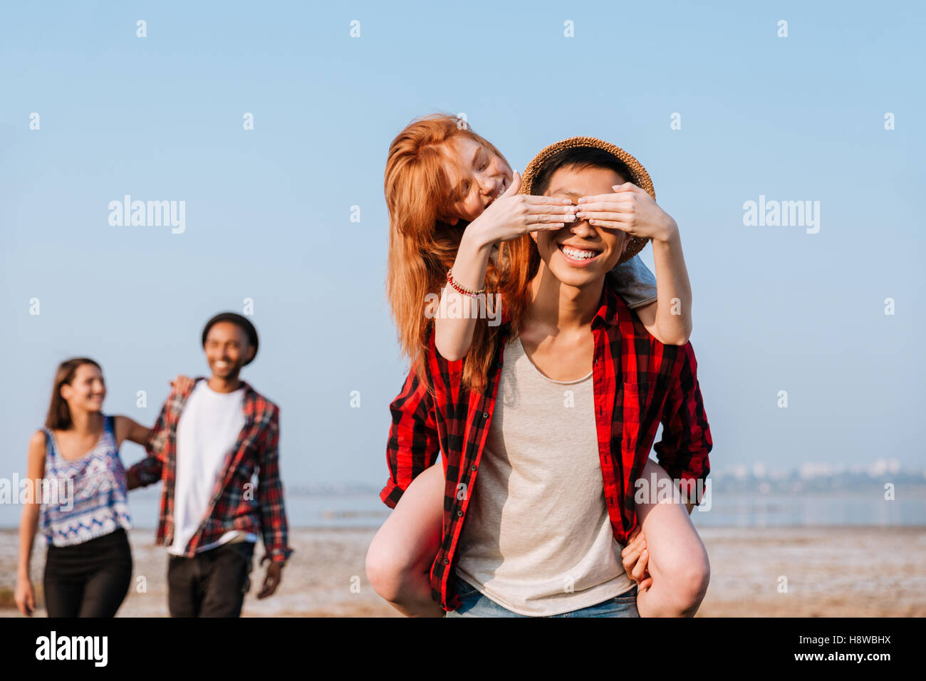 Felice redhead giovane donna coperta gli occhi del suo ragazzo da mani all'aperto Foto Stock