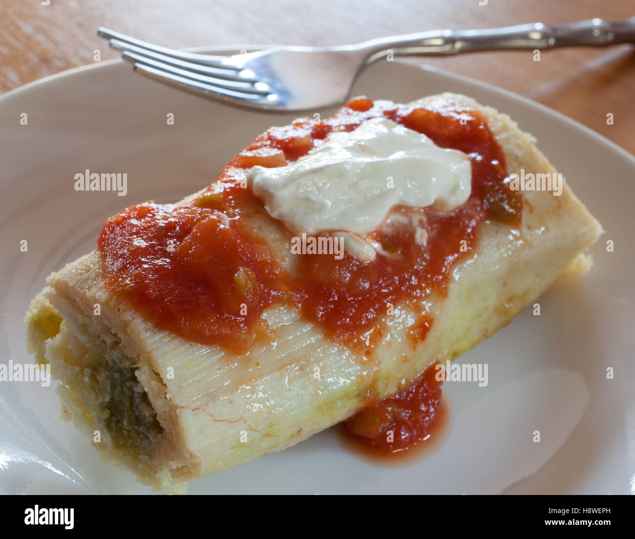 Tamale riempito con peperoncino verde con crema acida e salsa Foto Stock