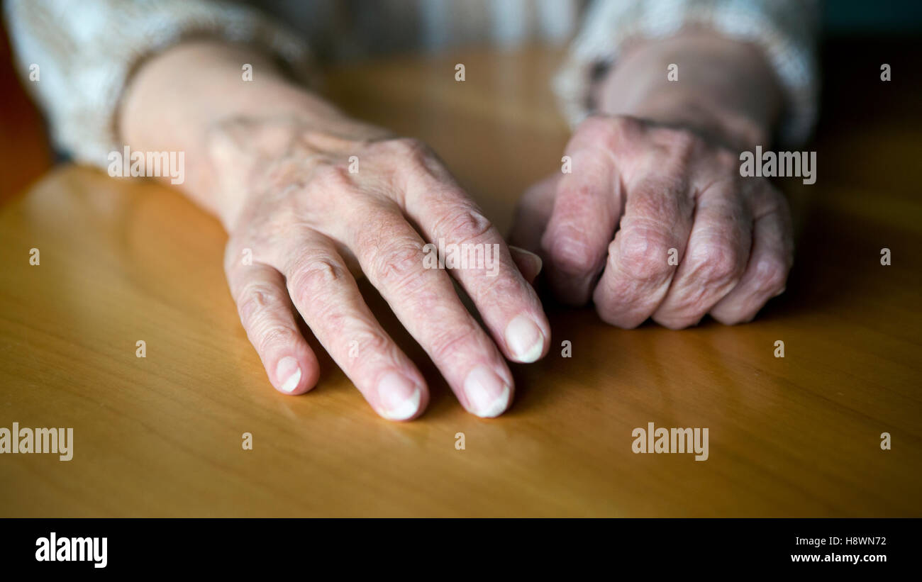 Vista dettagliata del vecchio rugoso mani femminili in appoggio sul tavolo Foto Stock