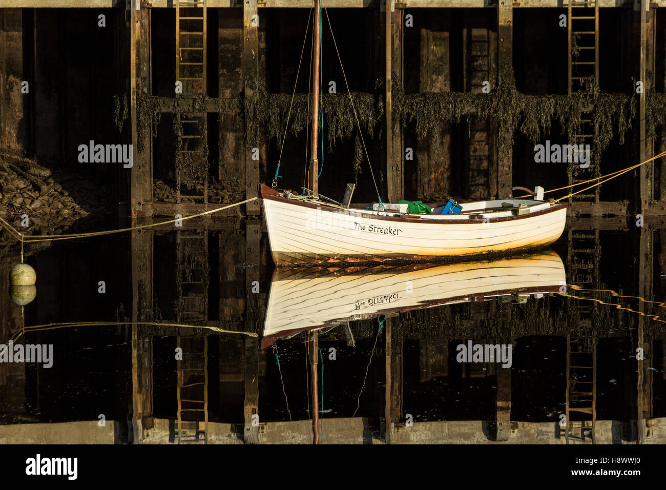 Clinker piccola barca da pesca legata a una parete del porto Foto Stock