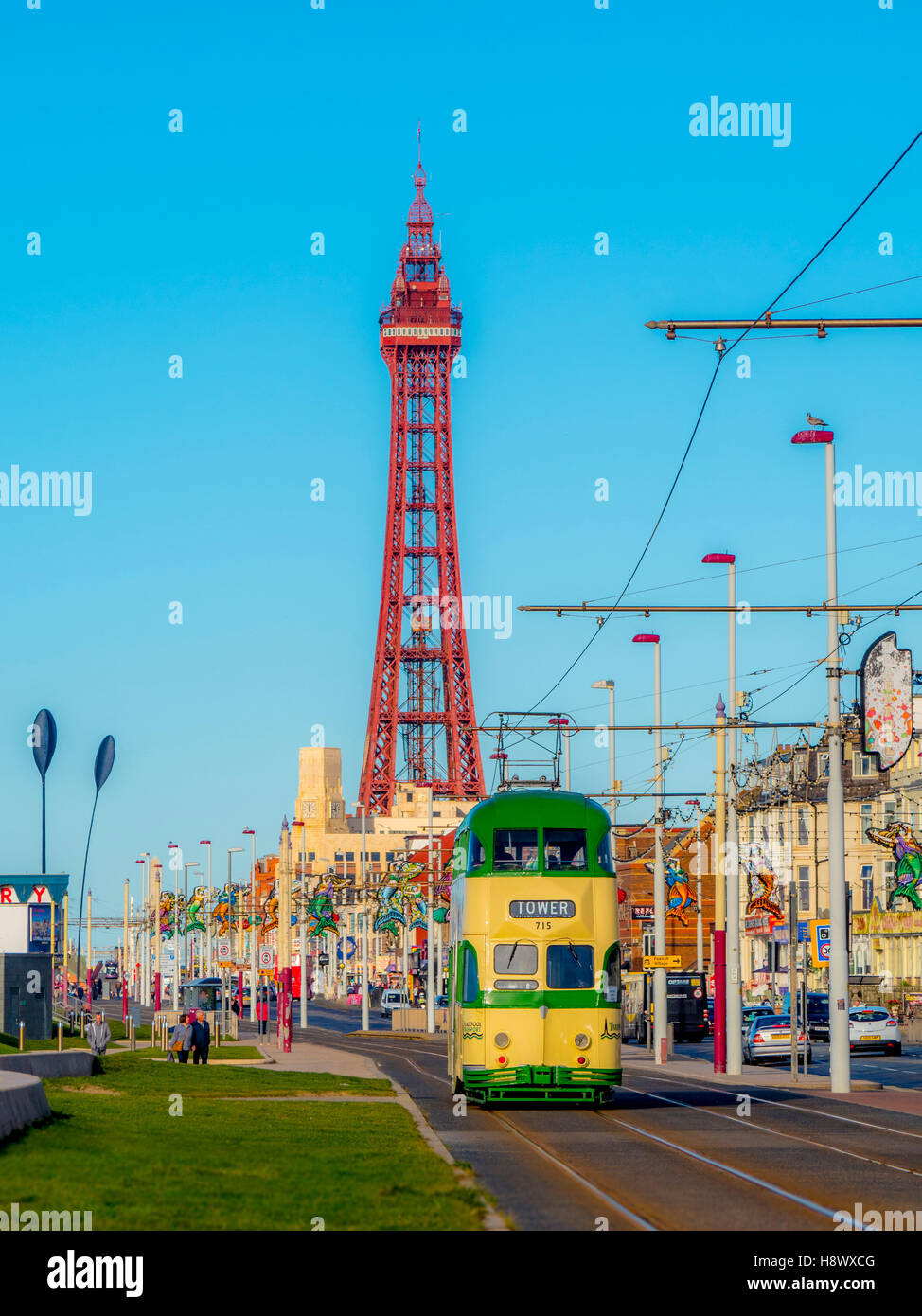 Tradizionali di tram che corre lungo la passeggiata sul lungomare con torre in background, Blackpool, Lancashire, Regno Unito. Foto Stock