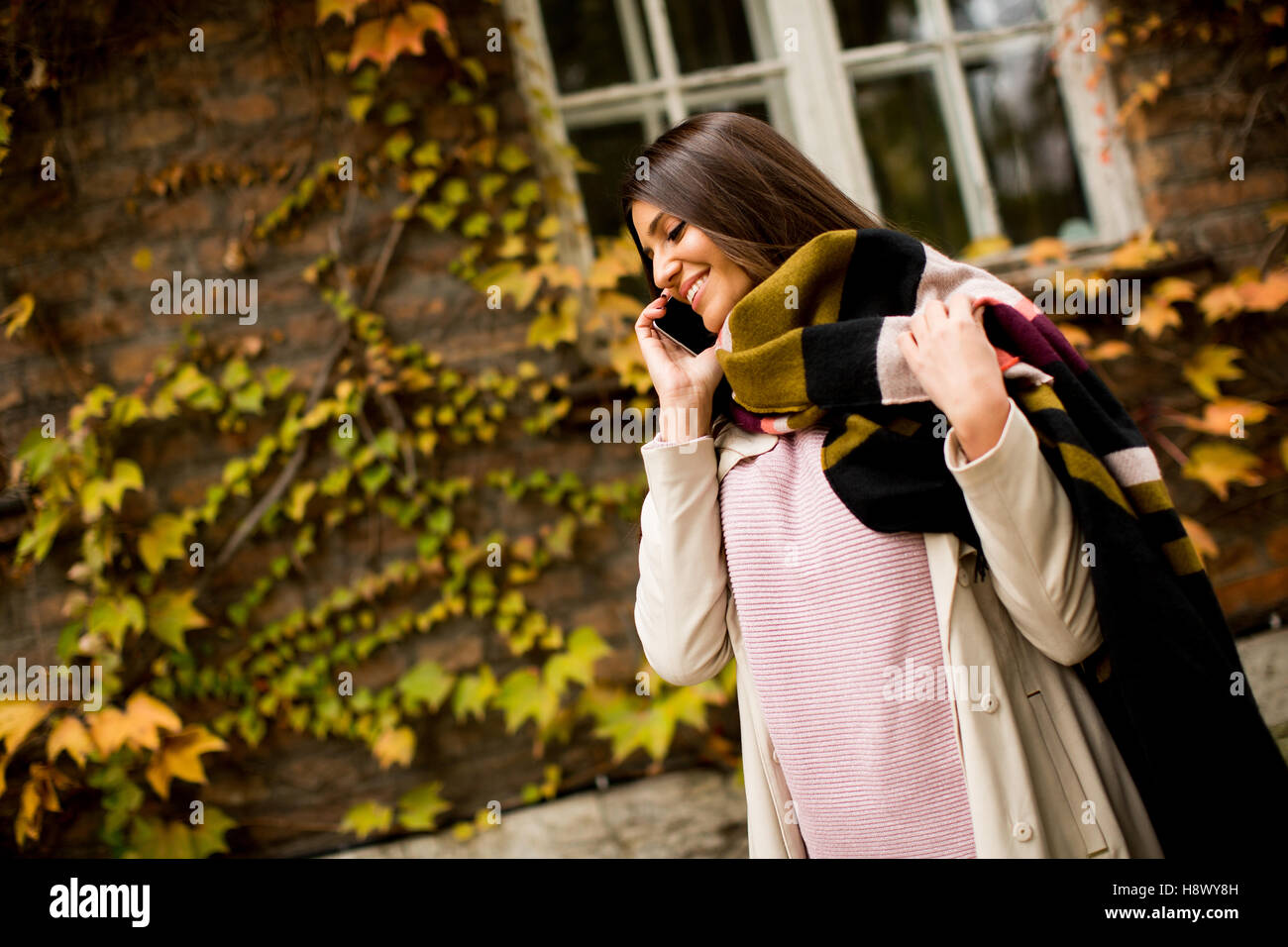 Giovane donna con un cellulare in autunno per esterno Foto Stock