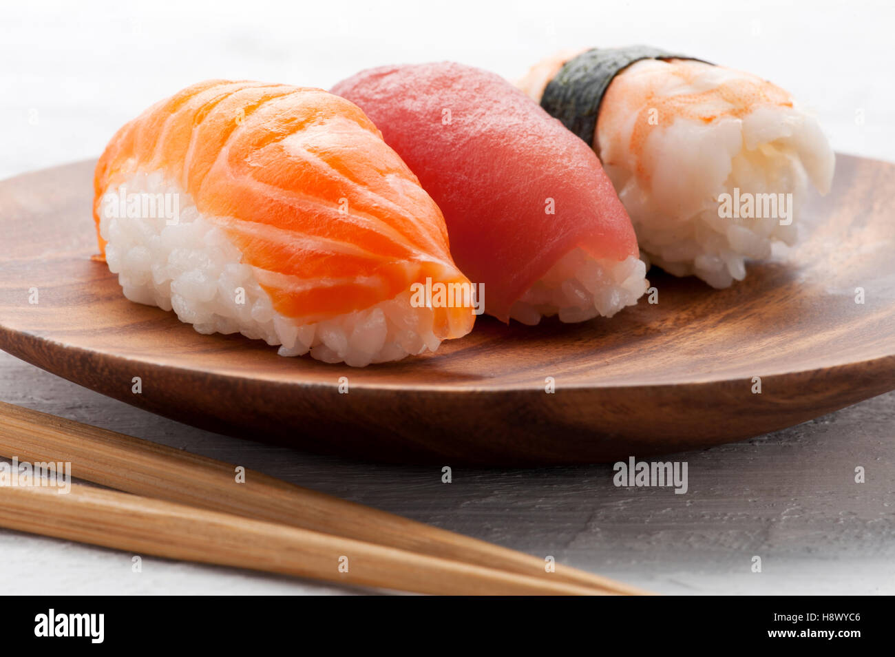Tre differenti Nighiri giapponese sushi tumuli e rabboccato con pesce fresco e di alghe servita su un piatto di legno per antipasti Foto Stock