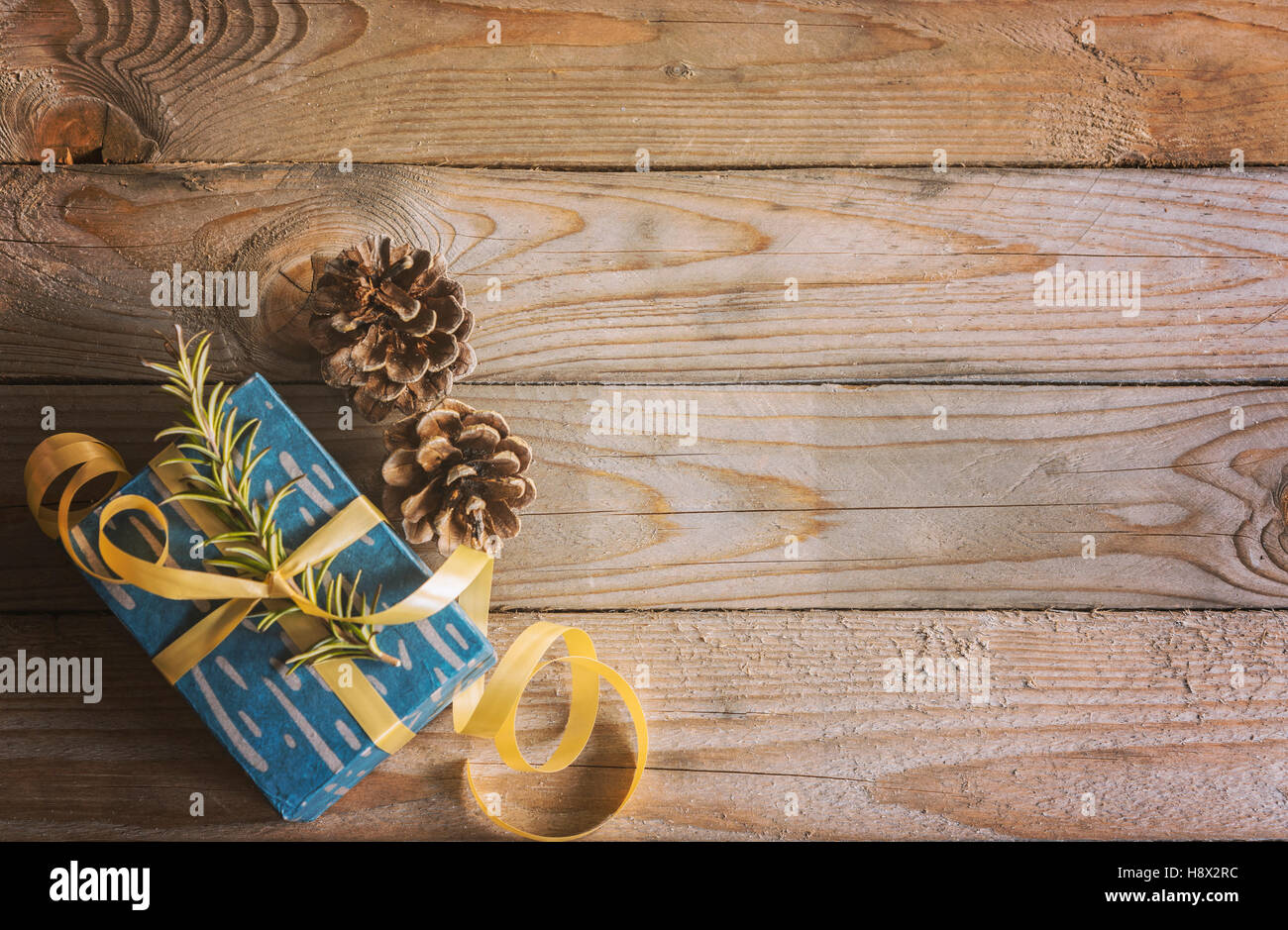 Immagine di un dono avvolto e pigne su sfondo di legno. Vintage sfondo di Natale. Foto Stock