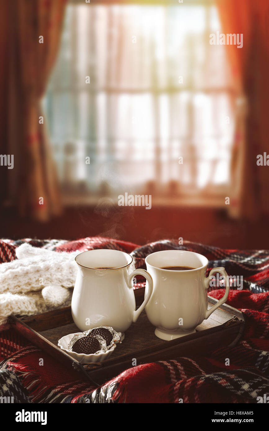 Cioccolata calda bevande sul tappeto di tartan con sole invernale il filtraggio attraverso la finestra Foto Stock