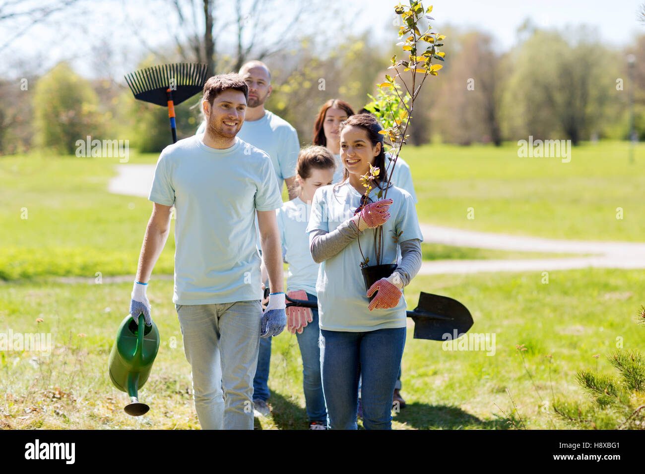 Un gruppo di volontari con alberi e rastrello in posizione di parcheggio Foto Stock
