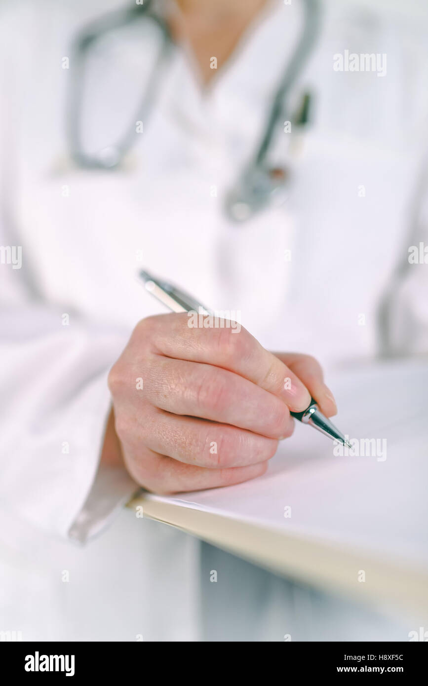 Medico donna in bianco uniforme la scrittura su carta per appunti medicinali soggetti a prescrizione medica. La donna come specialista in esame, er, la prevenzione delle malattie Foto Stock