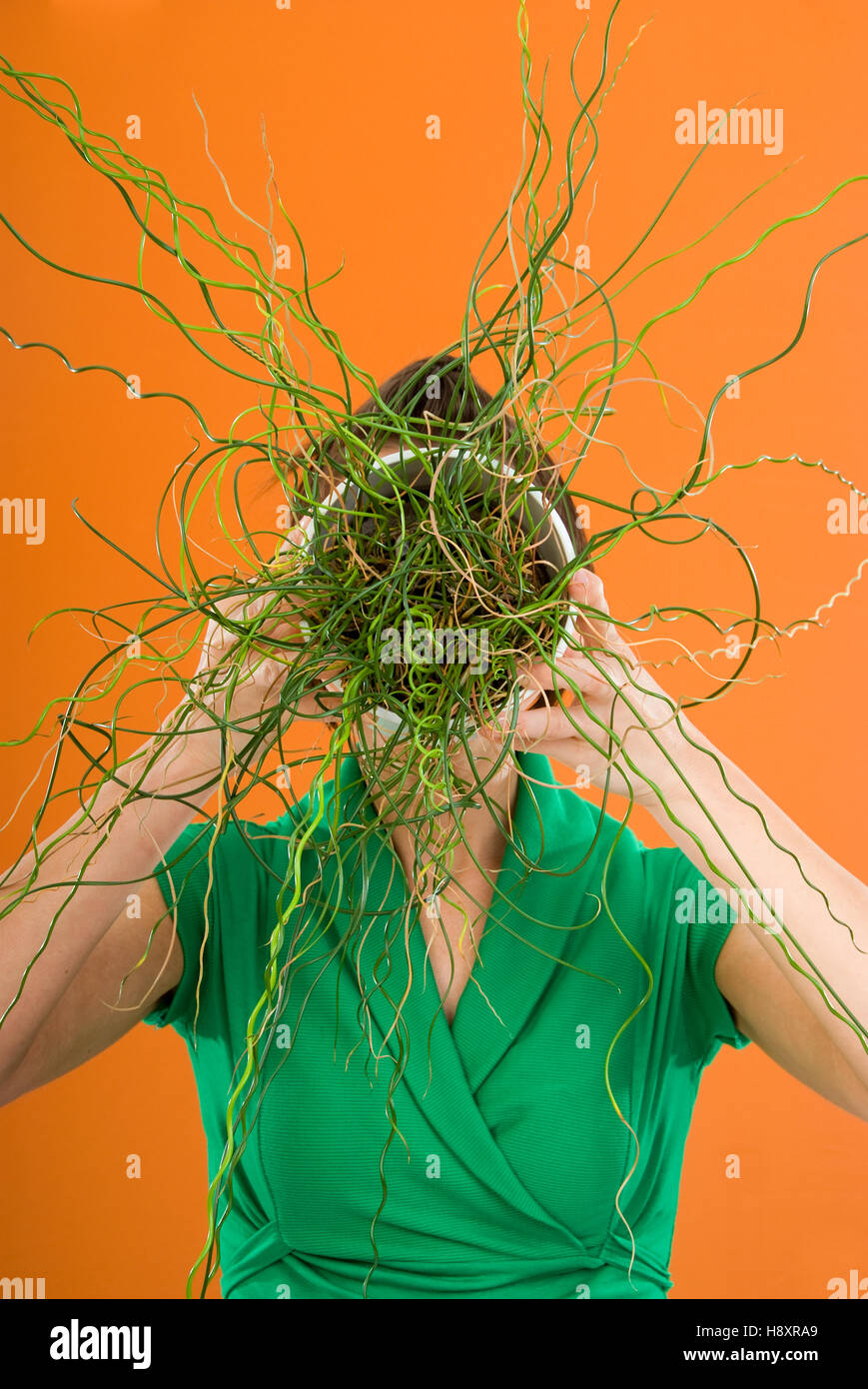 Donna con la pianta in vaso di fronte il suo volto Foto Stock