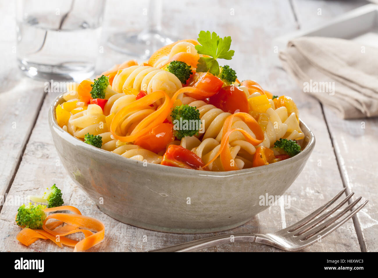 Fusilli con colorate pomodori, carote e broccoli su un bianco tavolo di legno della cucina italiana. Foto Stock