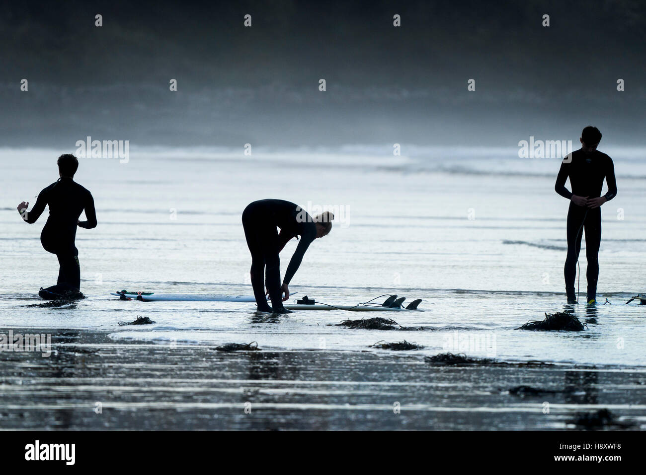 Tre i surfisti si prepara a navigare a Fistral in Newquay, Cornwall. Foto Stock
