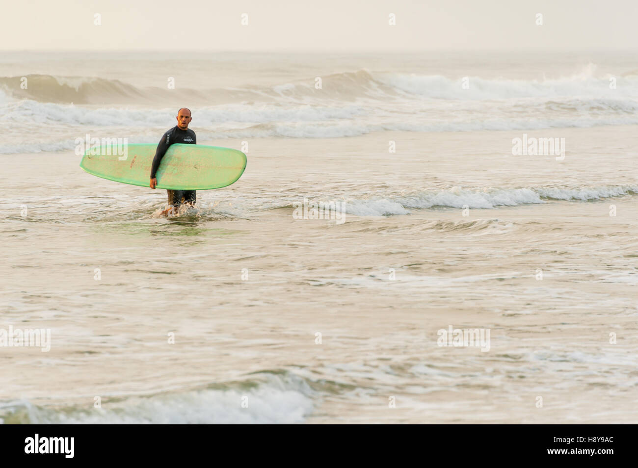 Surfer lasciando l'acqua dopo un sunrise 'dawn patrol' sessione di surf in spiaggia di Jacksonville, Florida, Stati Uniti d'America. Foto Stock