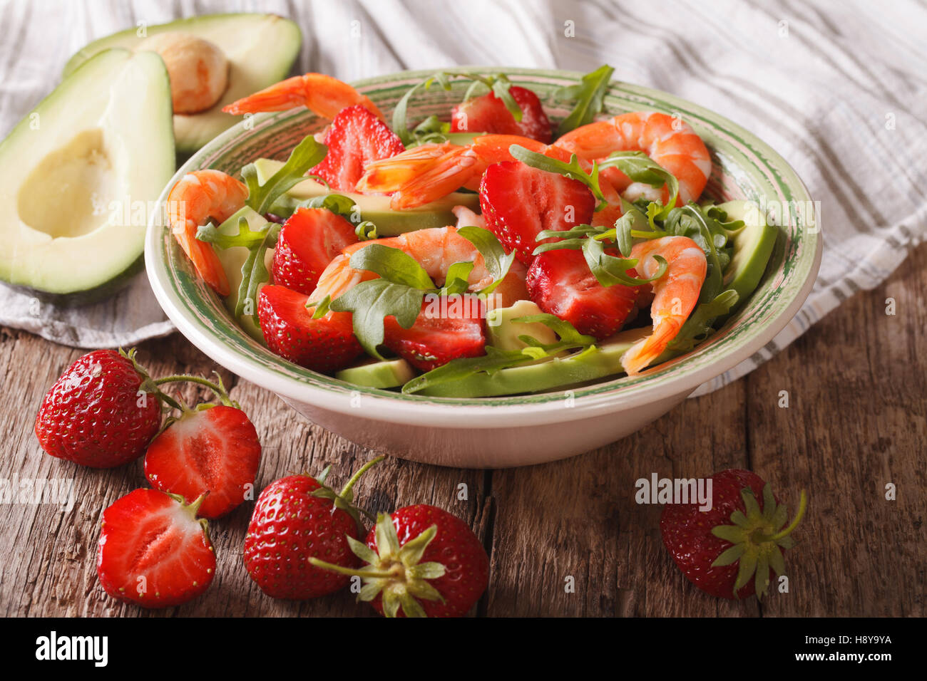 Cocktail con insalata di fragole, avocado, gamberi e rucola close-up su una piastra orizzontale. Foto Stock