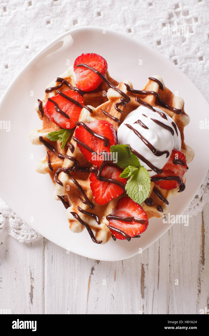 Cialde belghe con fragole e cioccolato topping su una piastra. Vista verticale da sopra Foto Stock