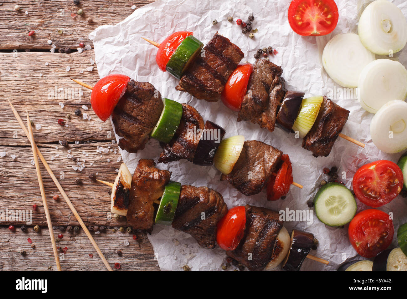 Shish kebab su spiedini con verdure vicino sul tavolo. vista orizzontale dal di sopra Foto Stock
