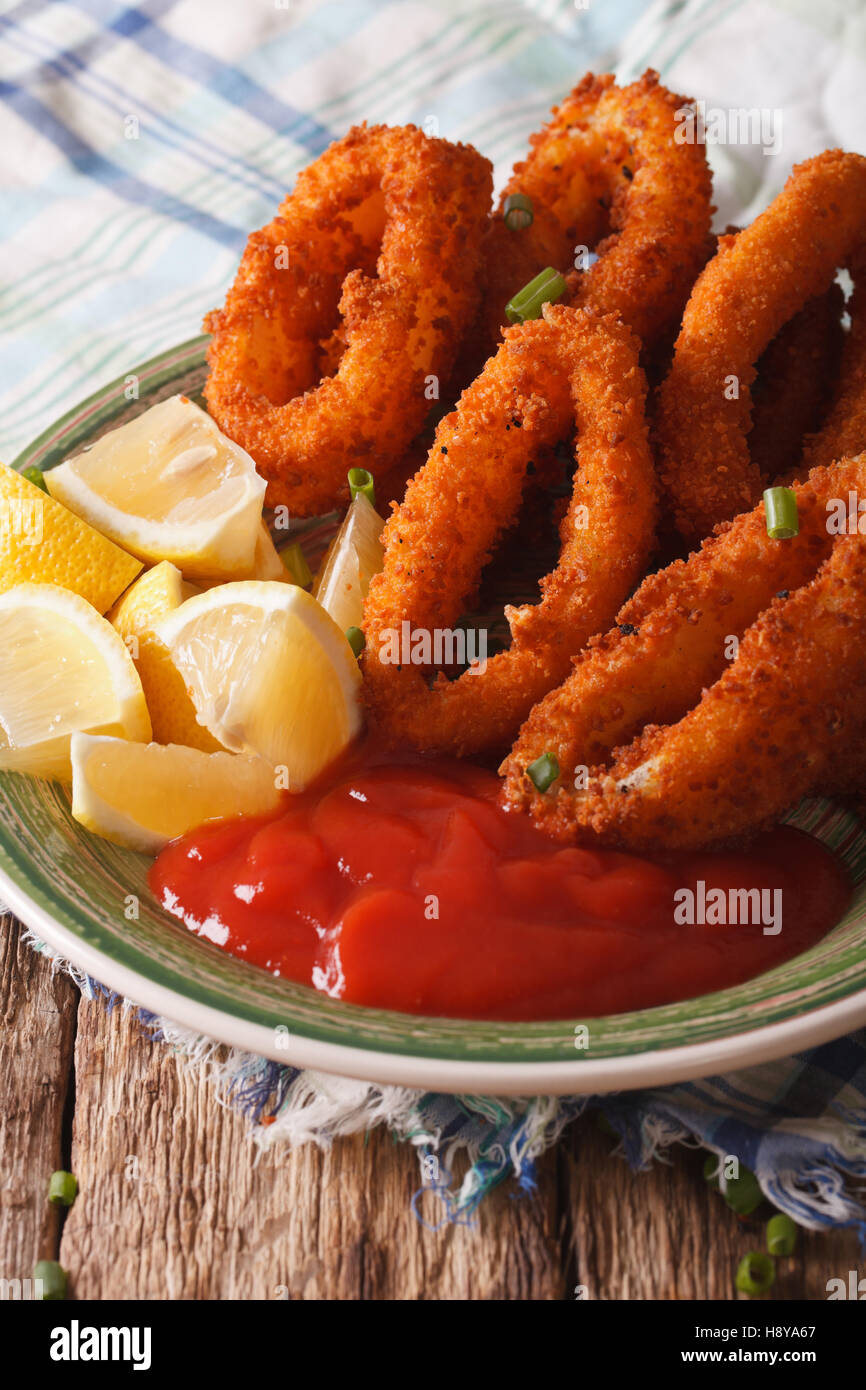 Anelli di totano fritto nel pangrattato close-up su una piastra con ketchup  e limone. In verticale Foto stock - Alamy
