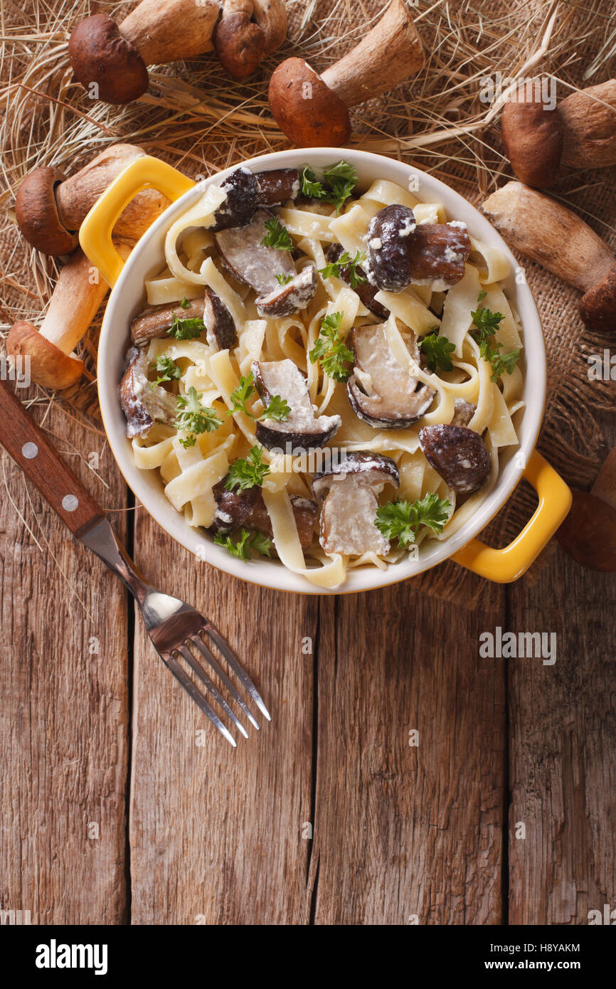 La pasta italiana Le Fettuccine con funghi selvatici in salsa alla panna close-up in una pentola di giallo. Vista verticale da sopra Foto Stock