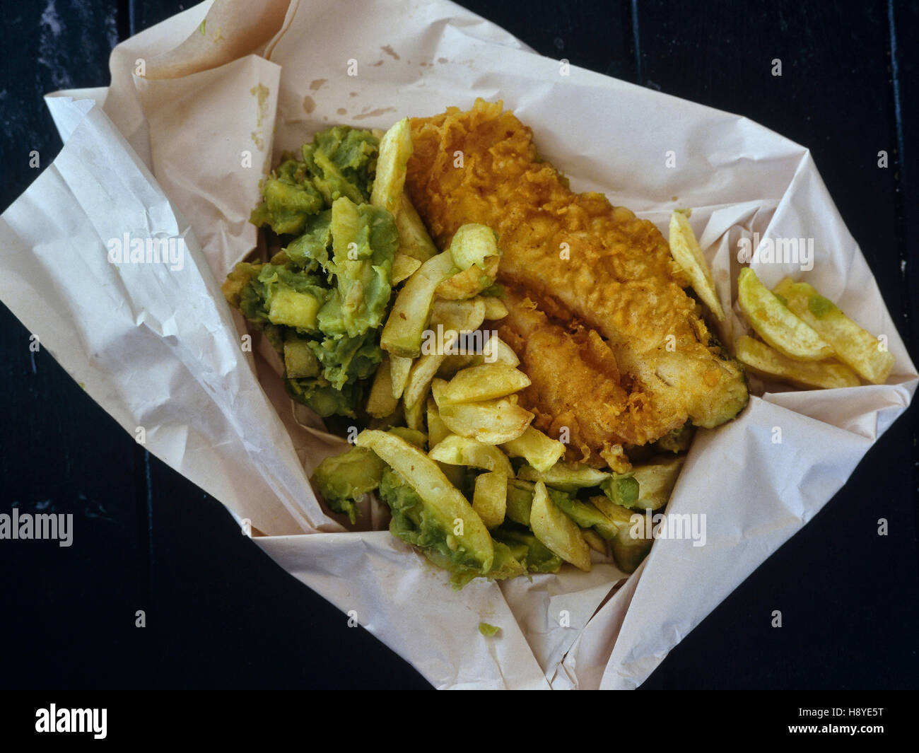 Takeaway pesce e patatine con fiacco piselli avvolto in carta bianca Foto Stock