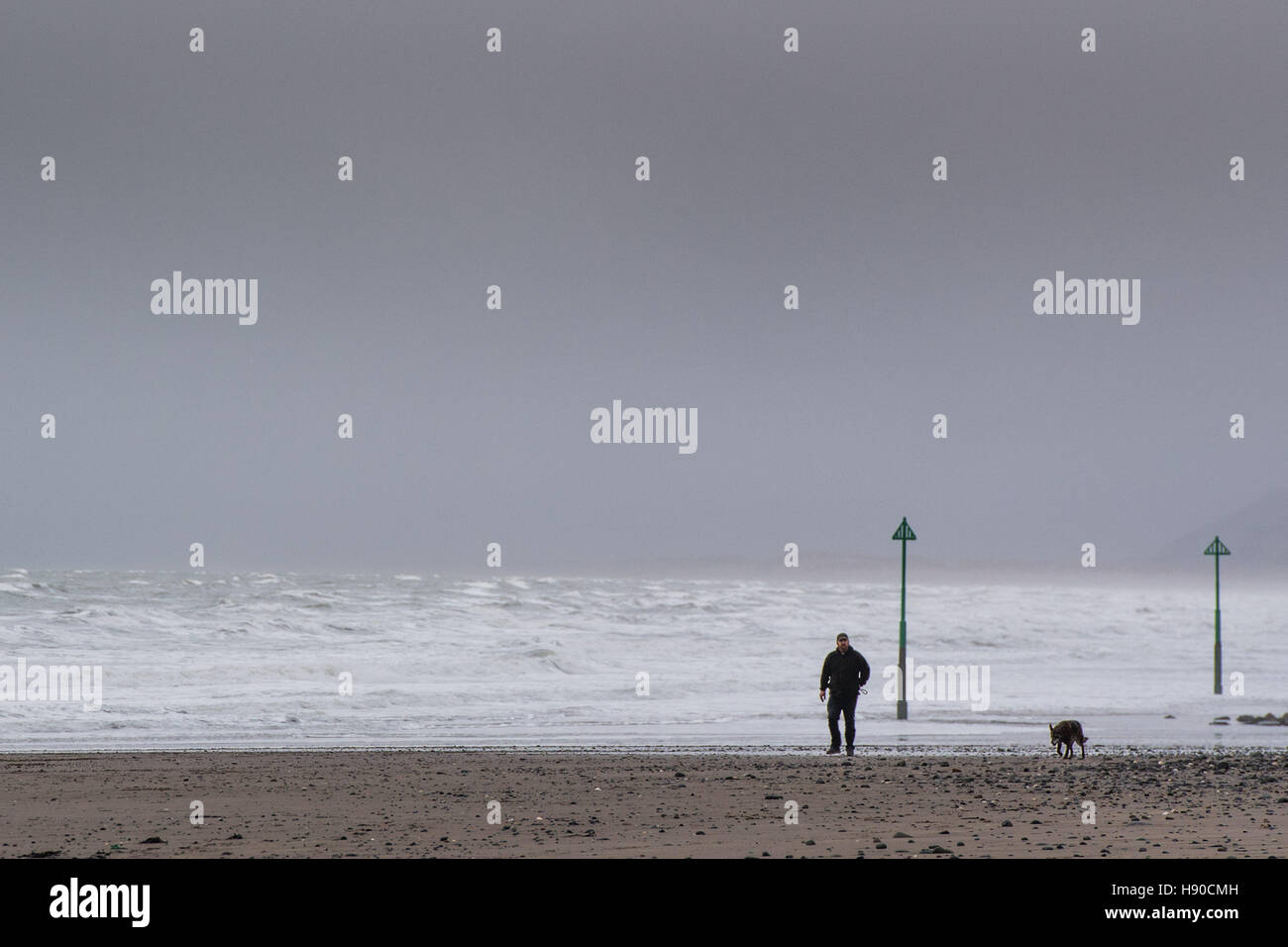 Borth, Cardigan Bay, Ceredigion , Wales UK. Martedì 10 Gennaio 2017 UK Meteo: un uomo che cammina il suo cane sulla spiaggia di Borth sulla West Wales coast su un blustery nuvoloso giorno. Previsioni del tempo per le prossime 25 ore è per sempre più forti venti in gran parte ovest del Regno Unito e per la neve per arrivare dal weekend Credito: keith morris/Alamy Live News Foto Stock