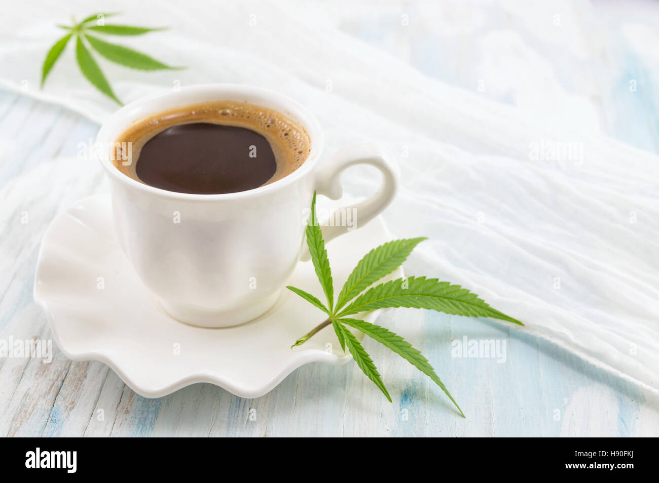 Caffè caldo e foglie di marijuana su un tavolo Foto Stock