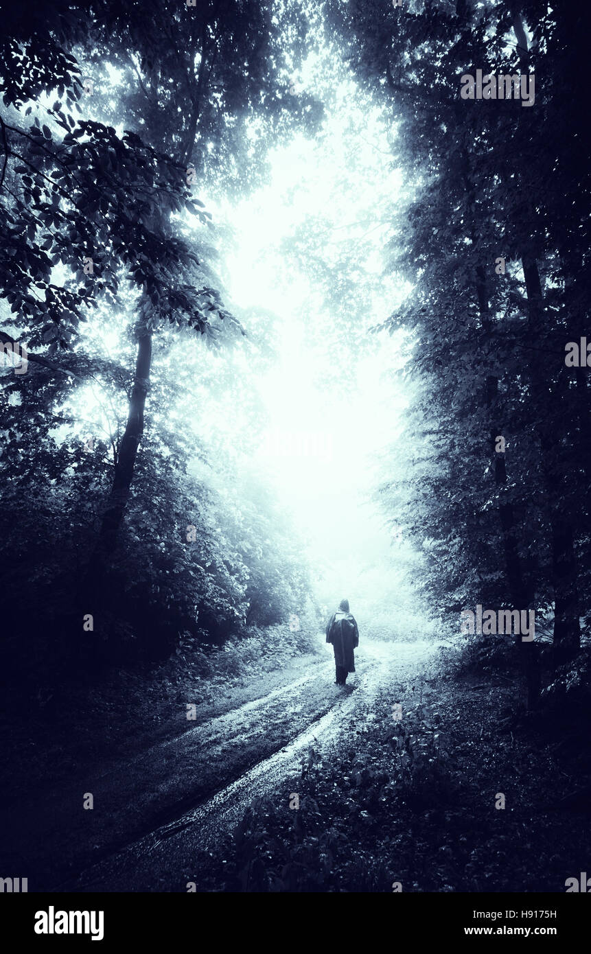 Uomo che cammina sulla foresta buia strada sul giorno di pioggia Foto Stock