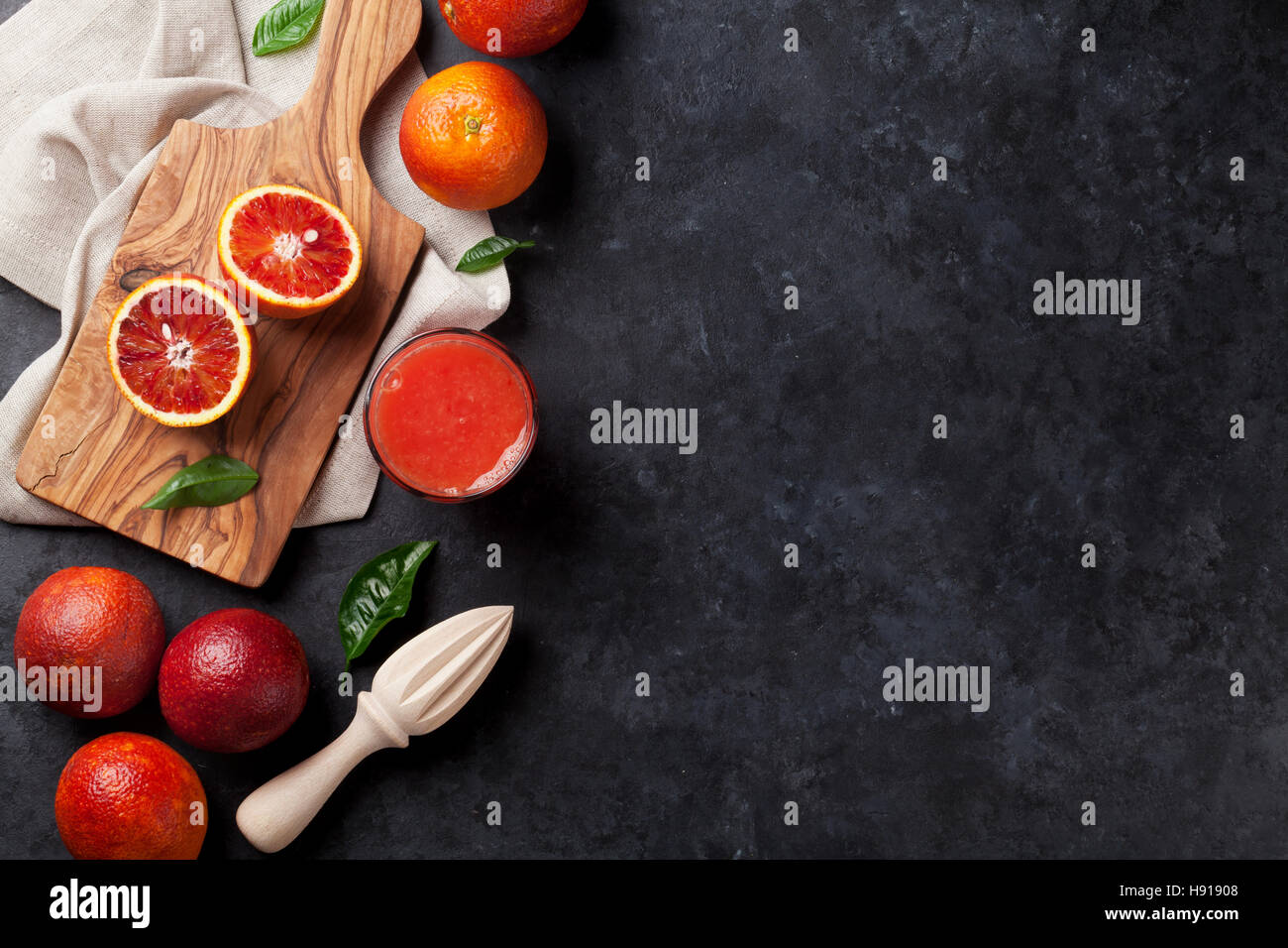 Agrumi freschi e rosso succo di arancia in pietra scura sullo sfondo. Vista da sopra con lo spazio di copia Foto Stock