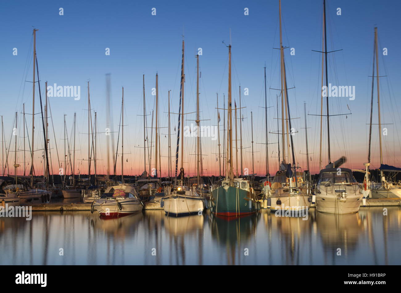 Barche a vela in porto al tramonto con esposizione lunga Foto Stock