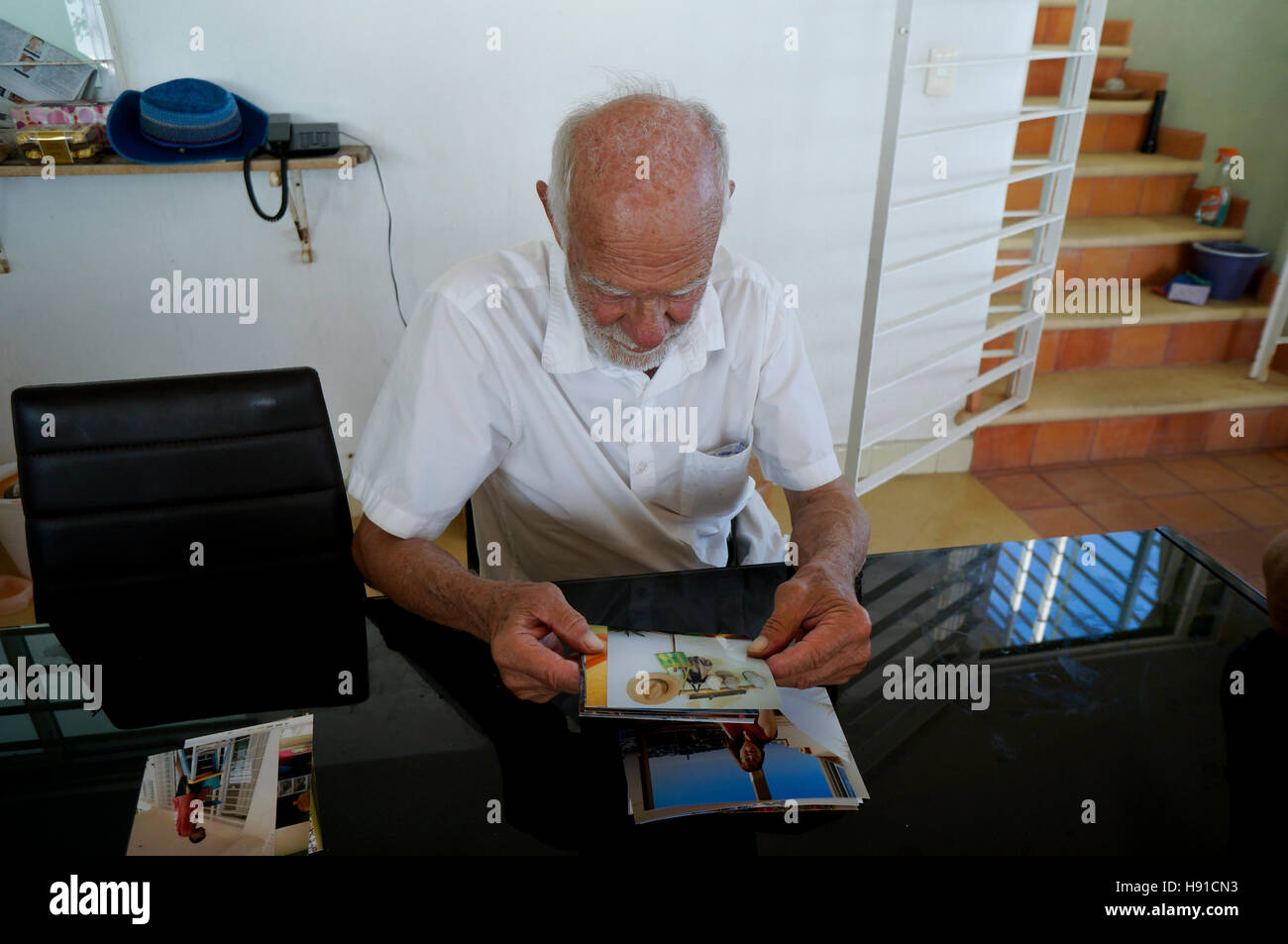 Uomo anziano con alzhiemers guardando le foto di famiglia e vacanza. Foto Stock