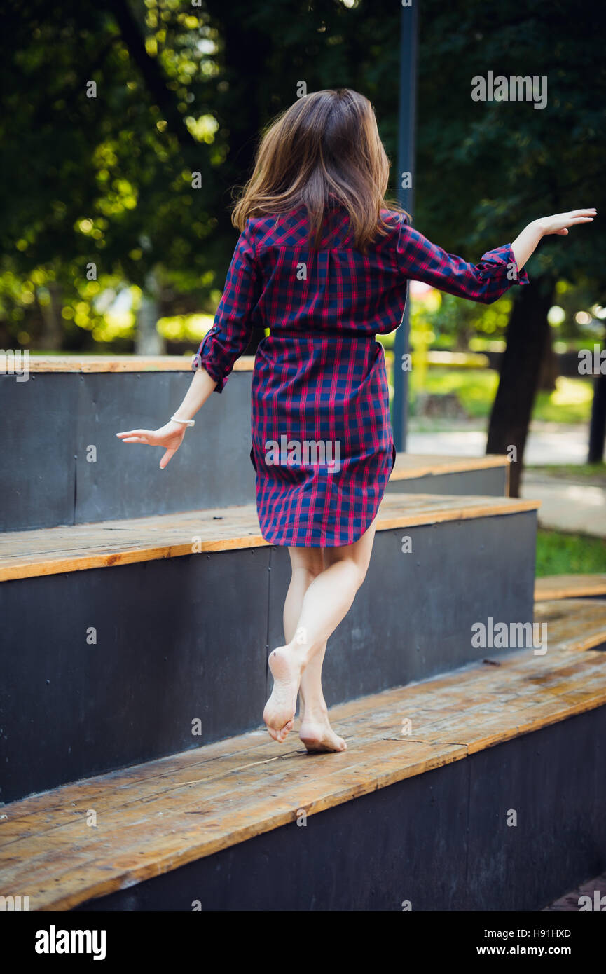 Ragazza fa piroettare camminando su un tiptoes contro d'estate il parco. Foto Stock