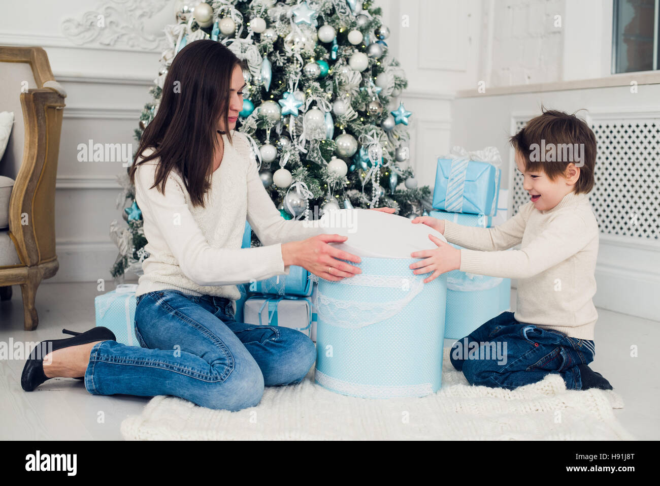 Donna e bambino controllando i regali di Natale a casa Foto Stock