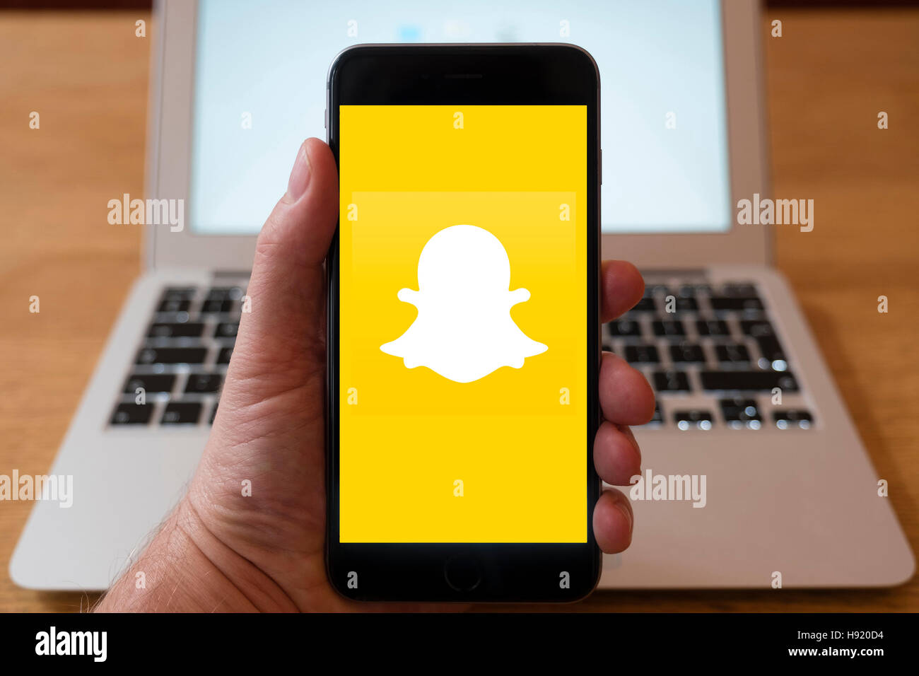 Utilizzo di iPhone smart phone per visualizzare il logo del sito web di Snapchat social media app Foto Stock