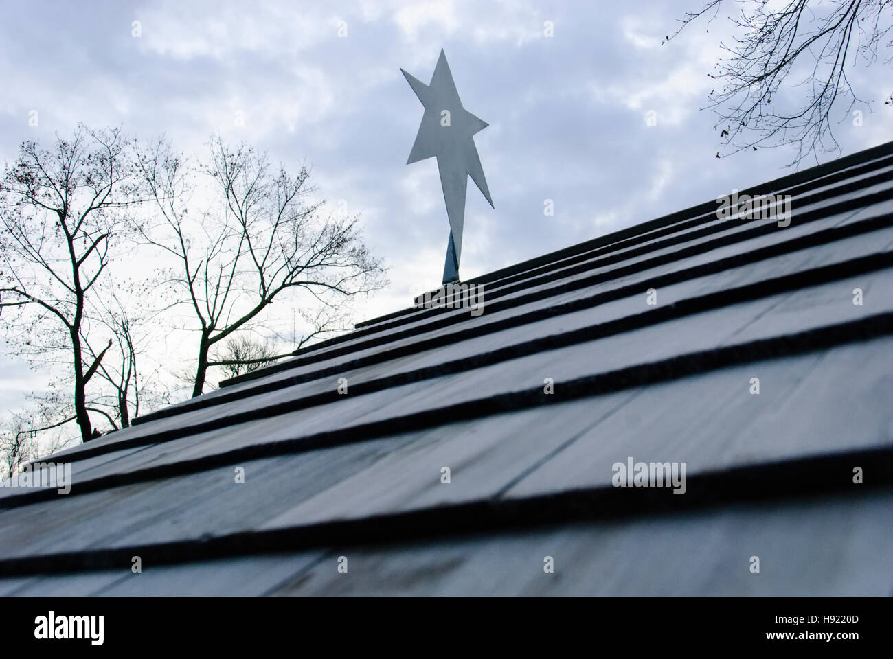 Stella di metallo ritaglio sul tetto contro il cielo nuvoloso. Foto Stock