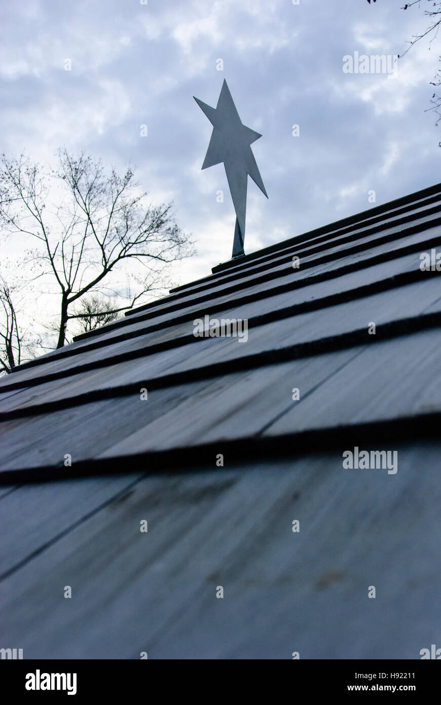 Stella di metallo ritaglio sul tetto contro il cielo nuvoloso. Foto Stock