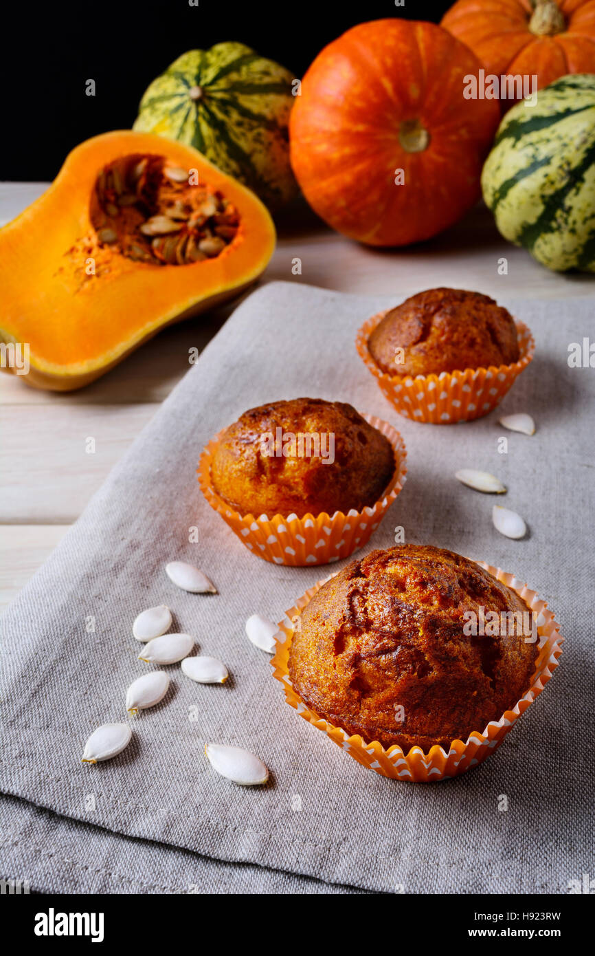Muffin di zucca in involucri di colore arancione con i semi di zucca. Caduta in casa stagionale cibo vegetale. Sana pasticceria vegetariana. Foto Stock