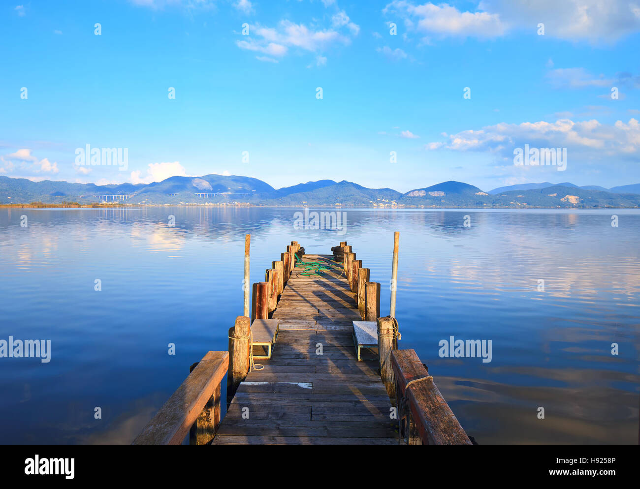 Il molo di legno o un pontile e su un lago blu tramonto e il cielo riflesso sull'acqua. Versilia Lago di Massaciuccoli, Toscana, Italia. Foto Stock