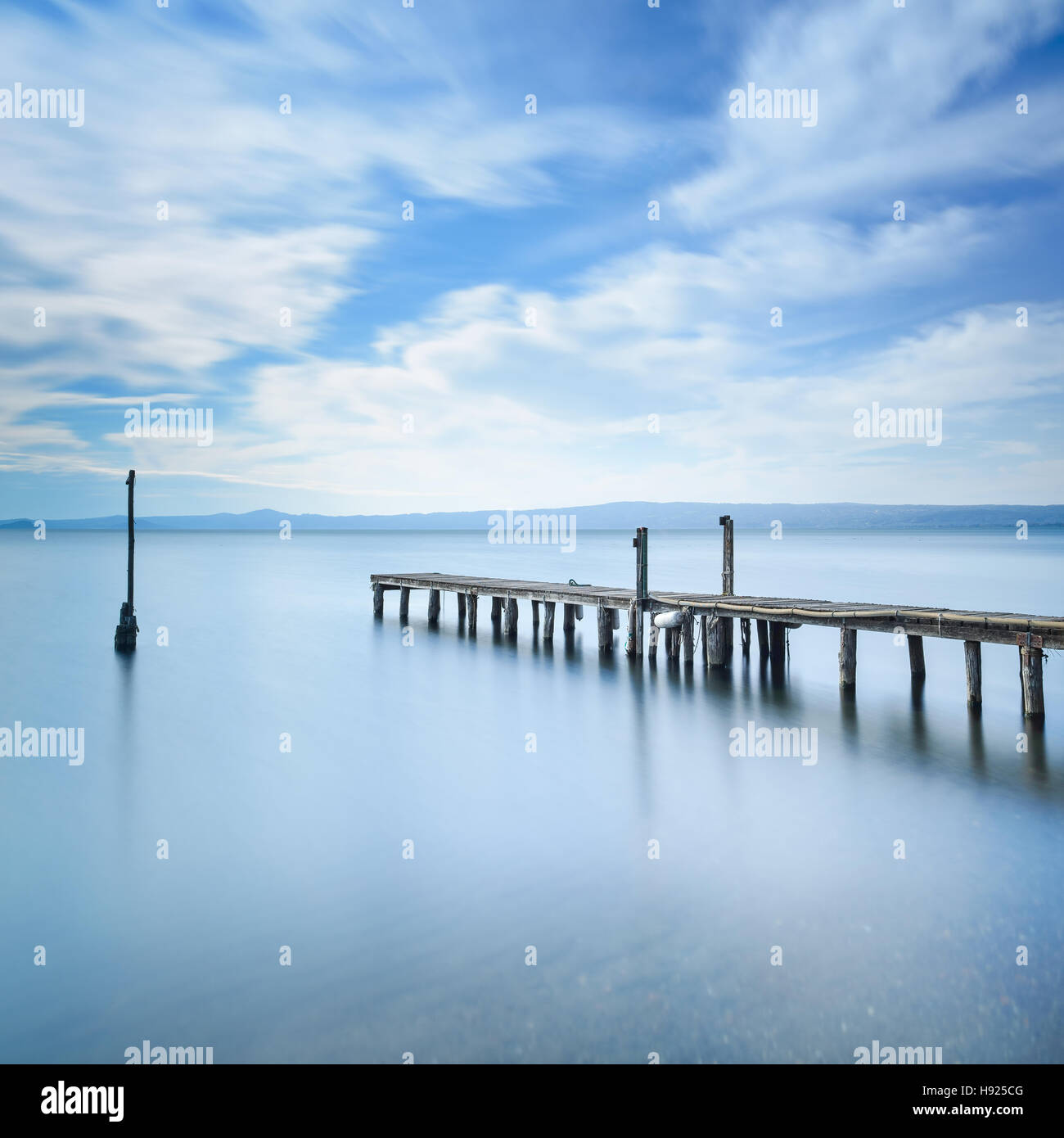 Il molo di legno o molo rimane su un lago blu del tramonto. Fotografie con lunghi tempi di esposizione Foto Stock
