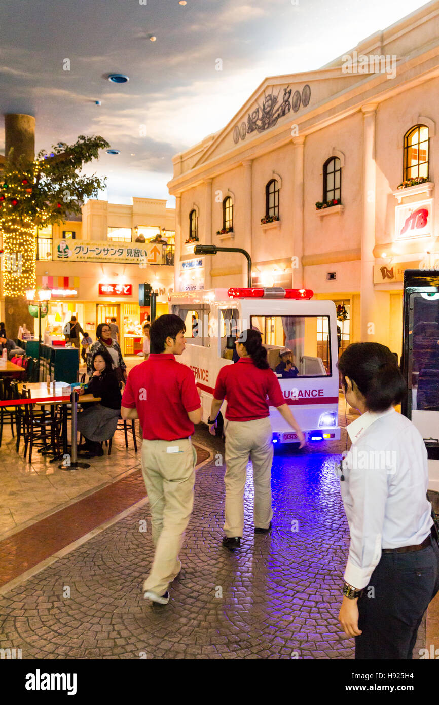 Giappone, Nishinomiya, KidZania, bambino activity center. Studio street con il personale che conduce i ragazzi di ambulanza come si trascina lungo. Foto Stock