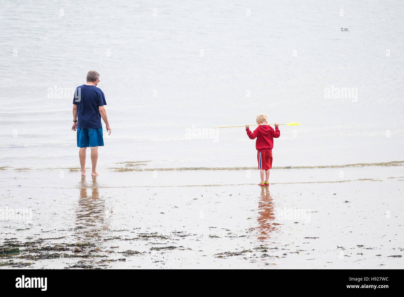 Un padre e figlio di stand sul foreshore a Soutrhend sul mare in Essex. Foto Stock