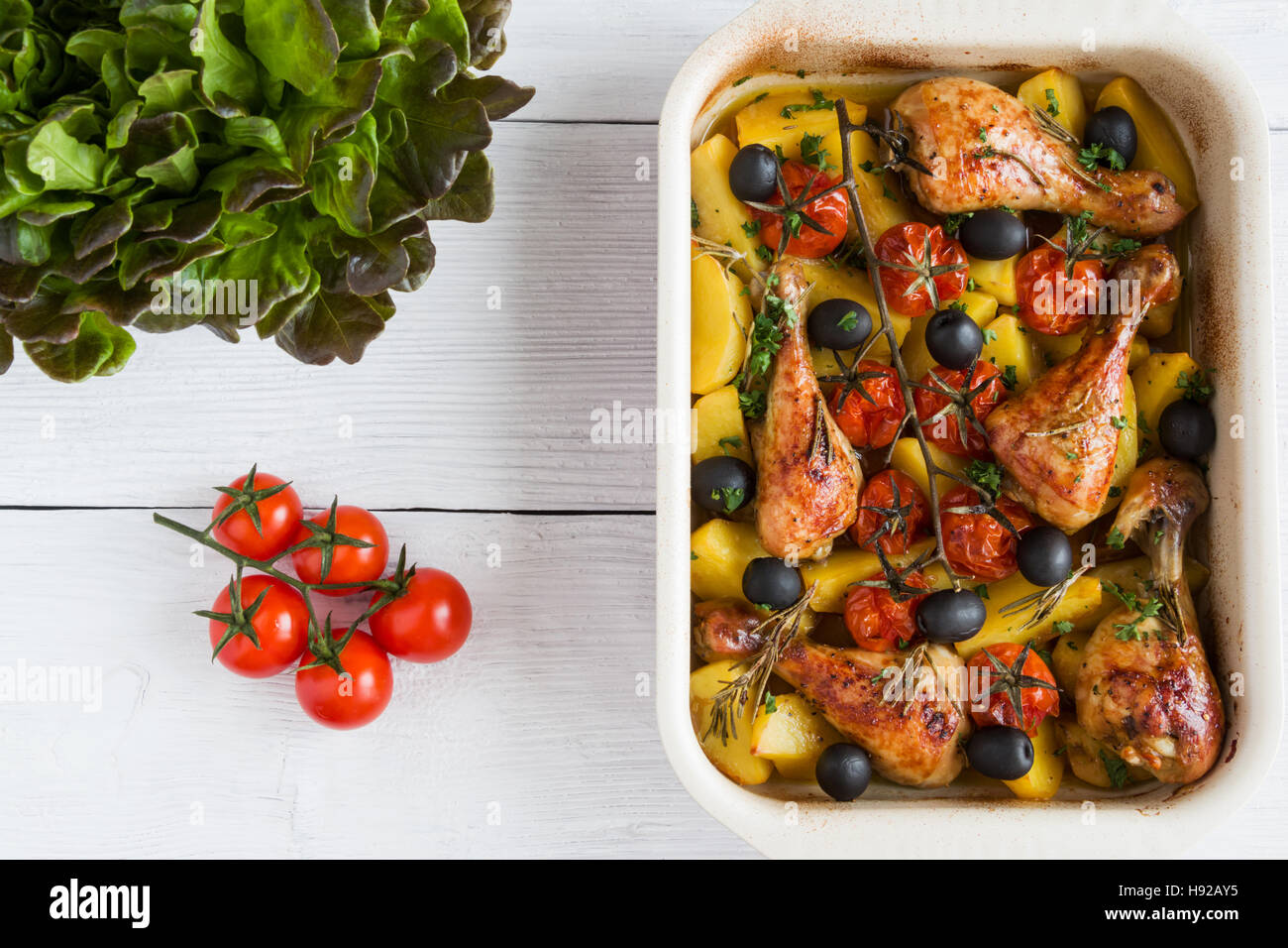 Il pollo al forno cosce di pollo disossate in rosso piatto. In cotto con  pomodorini e olive nere, rosmarino e patate. Bianco tavola di legno, vista  dall'alto Foto stock - Alamy