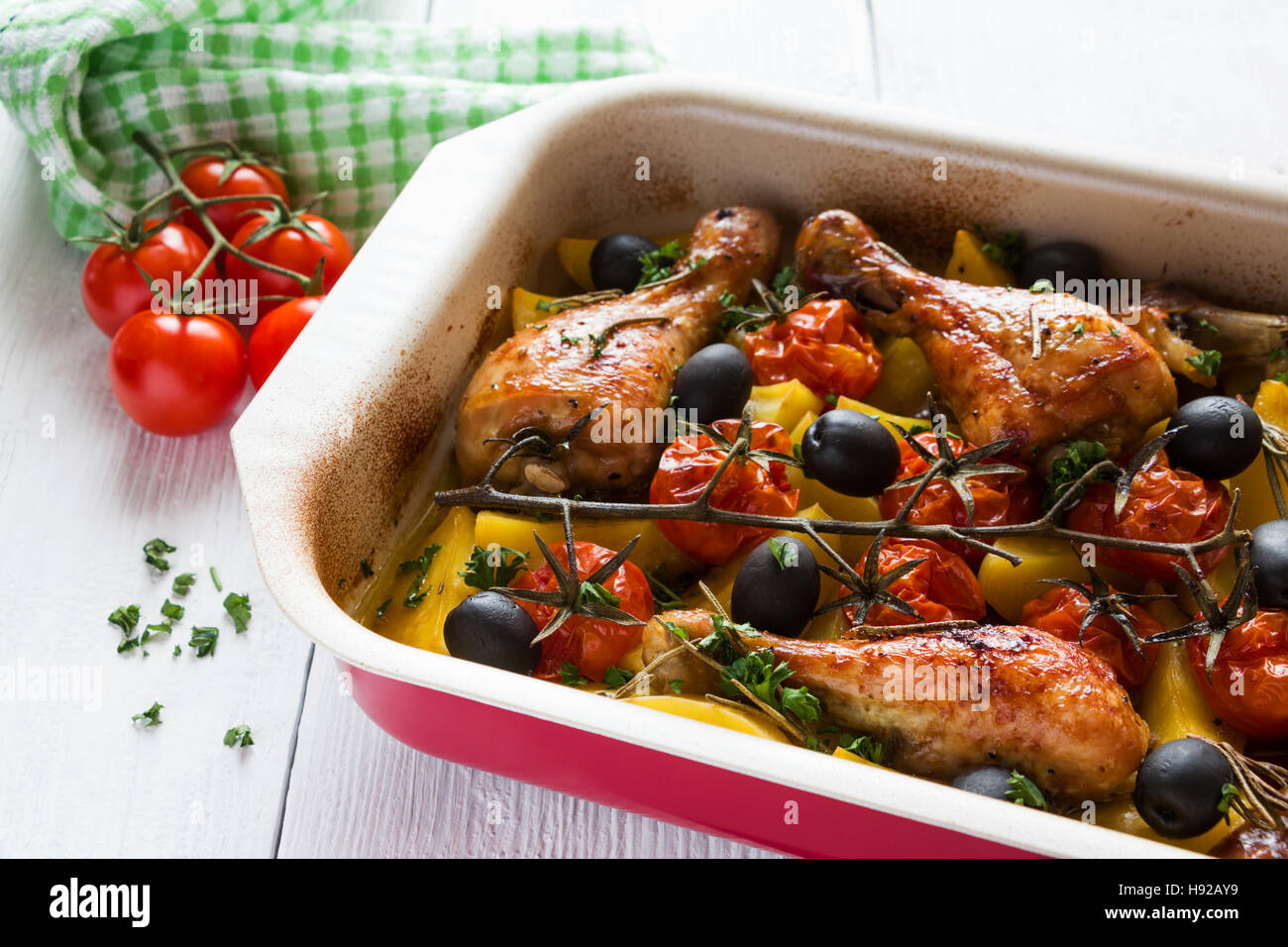 Il pollo al forno cosce di pollo disossate in rosso piatto. In cotto con  pomodorini e olive nere, rosmarino e patate. Bianco tavola di legno Foto  stock - Alamy