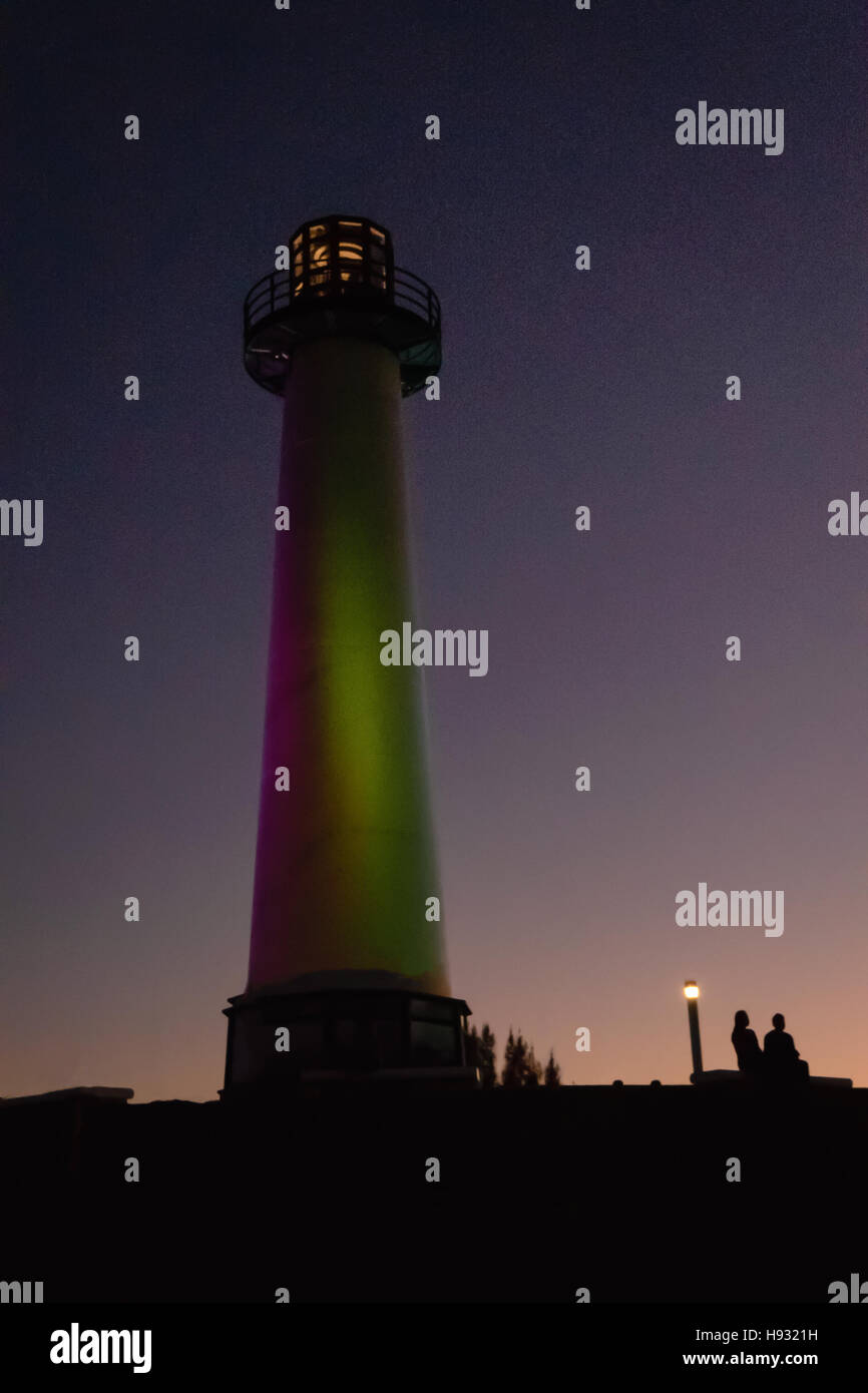 Matura in silhouette seduto sotto Long Beach Faro California di notte. Foto Stock