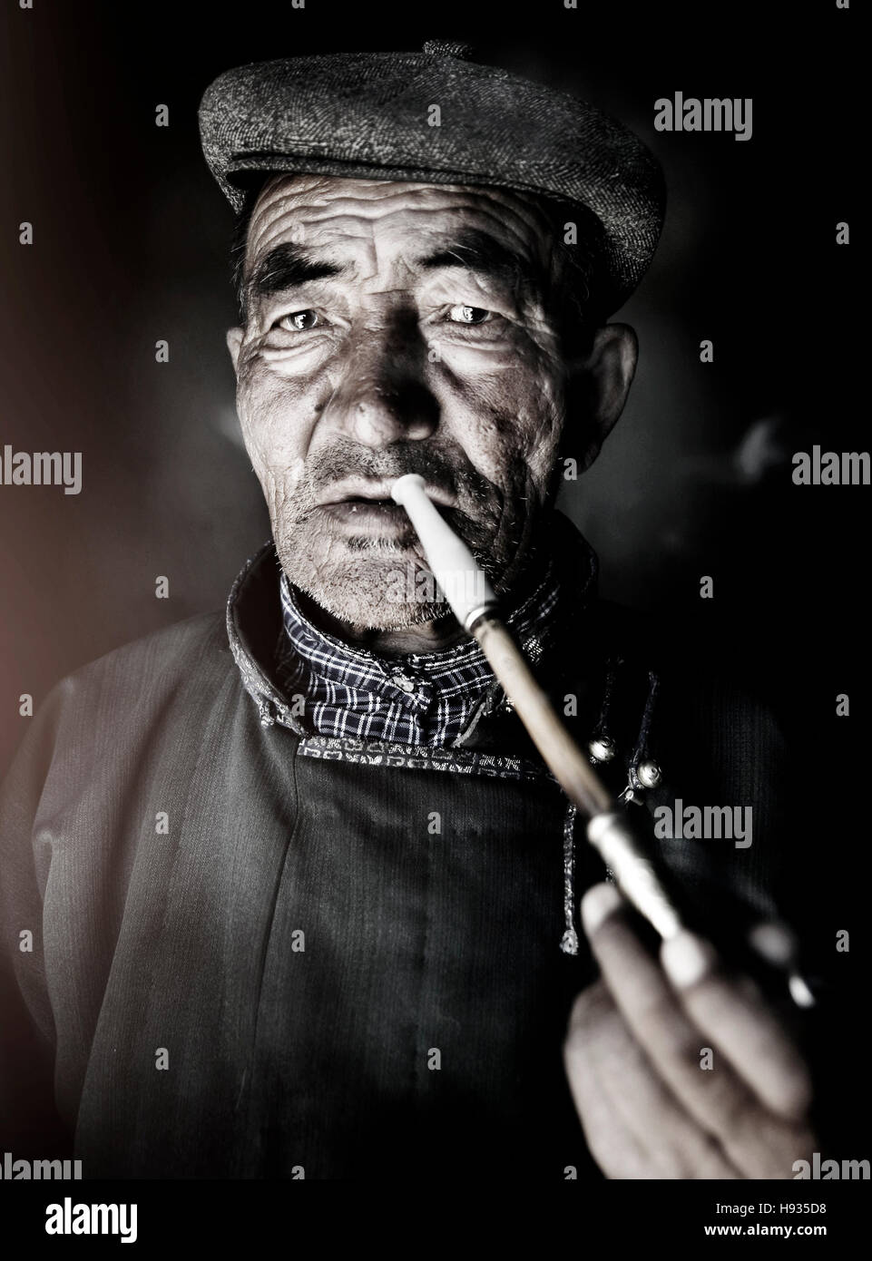 Il mongolo uomo in abito tradizionale di fumare un concetto della tubazione Foto Stock