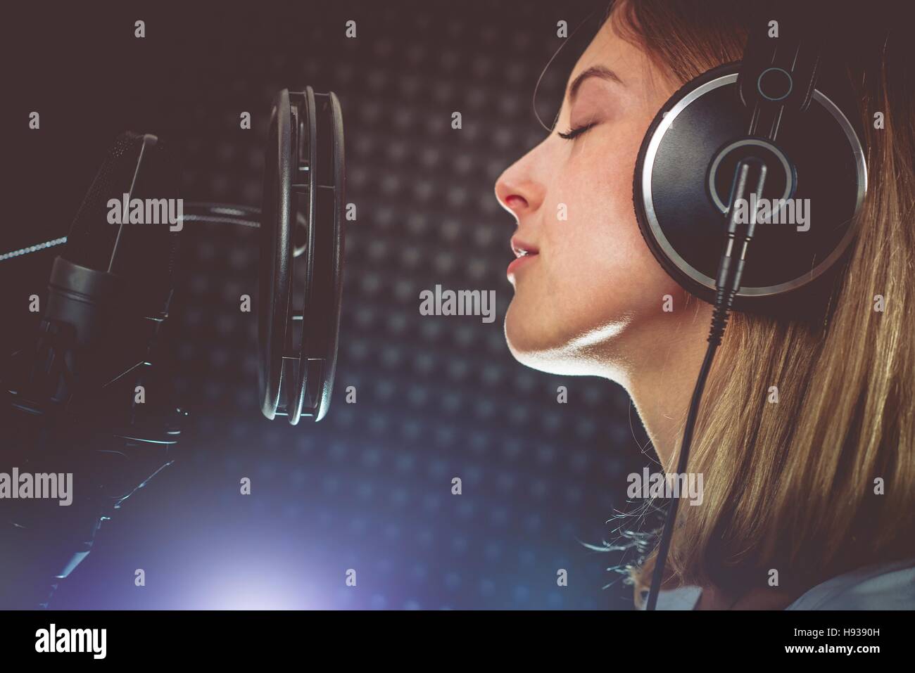 Appassionato di musica il cantante e il microfono. Giovane cantante caucasica nel suo 20s la registrazione di un album in studio di registrazione professionale. Il cantare con passione. Foto Stock