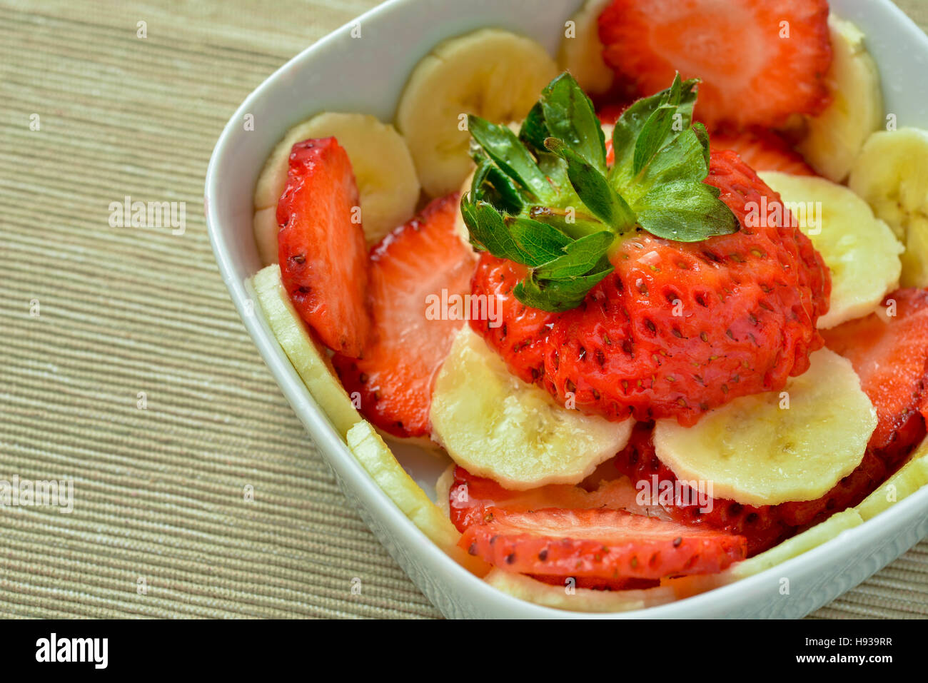 Ciotola con fragole e fette di banana nella luce naturale Foto Stock