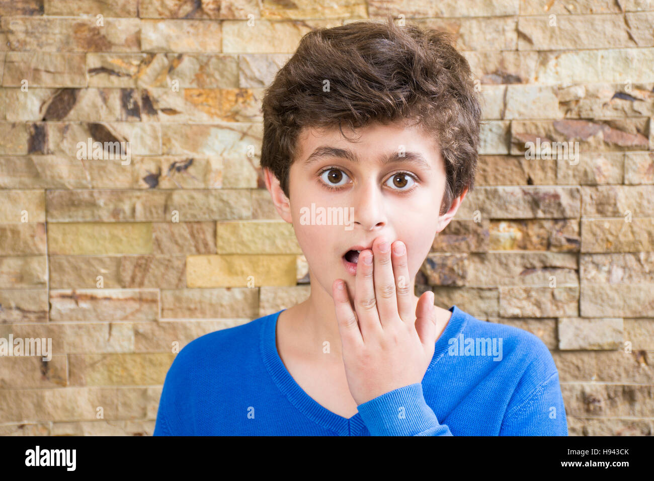 Scioccato dieci anni vecchio ragazzo che copre la bocca con la mano Foto Stock