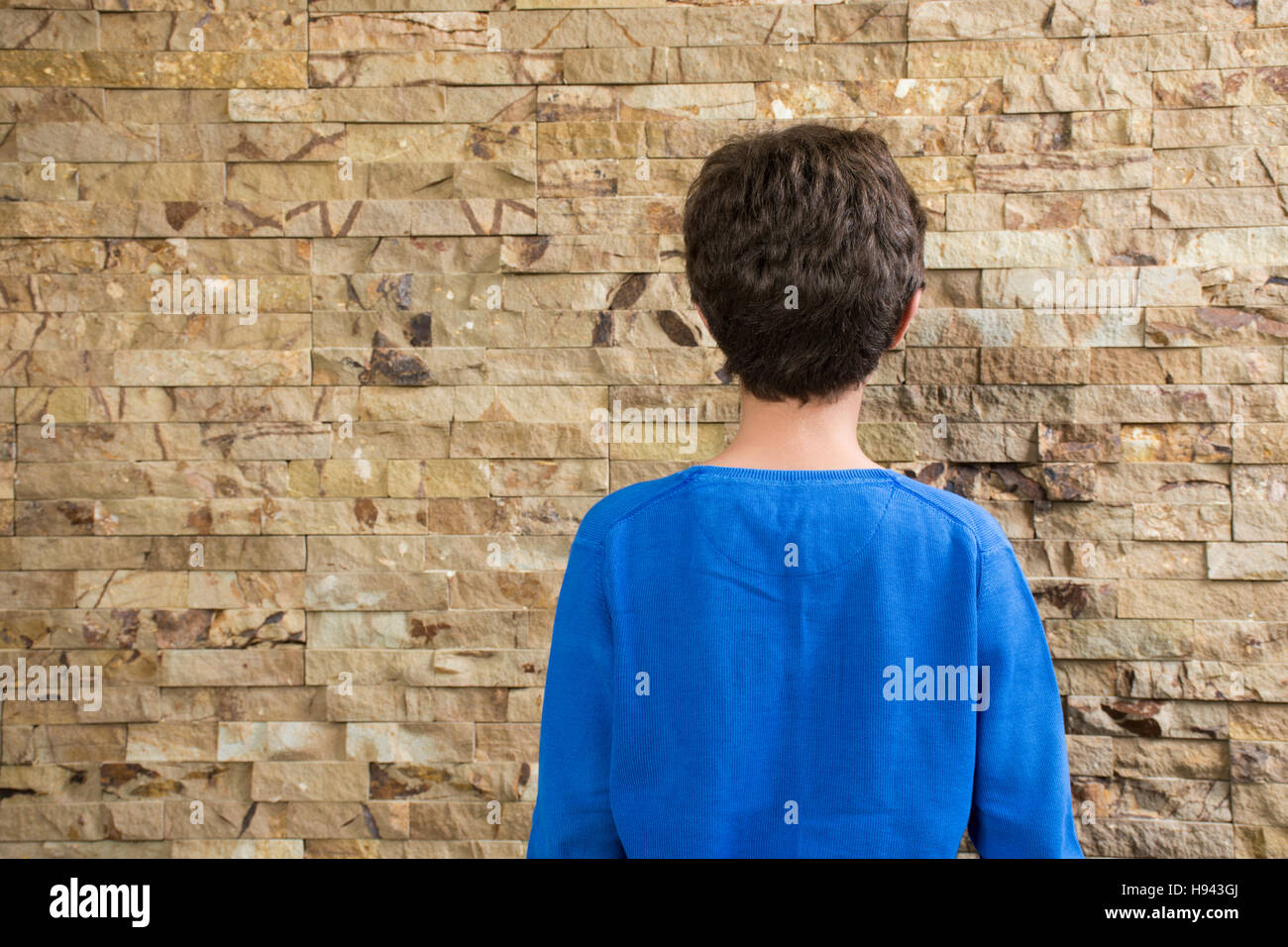 Vista posteriore di un dieci anni vecchio ragazzo rivolto verso la parete Foto Stock