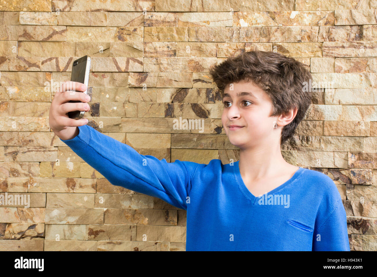 Dieci anni vecchio ragazzo prendendo un selfie foto utilizzando una fotocamera del cellulare Foto Stock